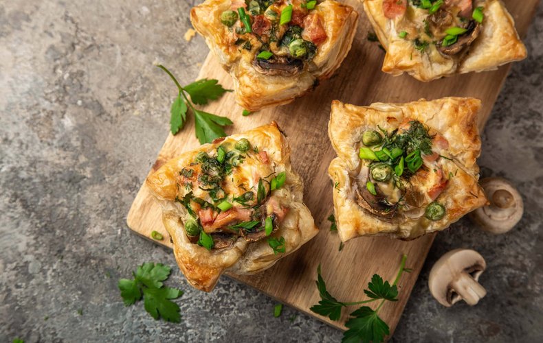 Cestitas de hojaldre con jamón cocido y champiñones sobre una tabla